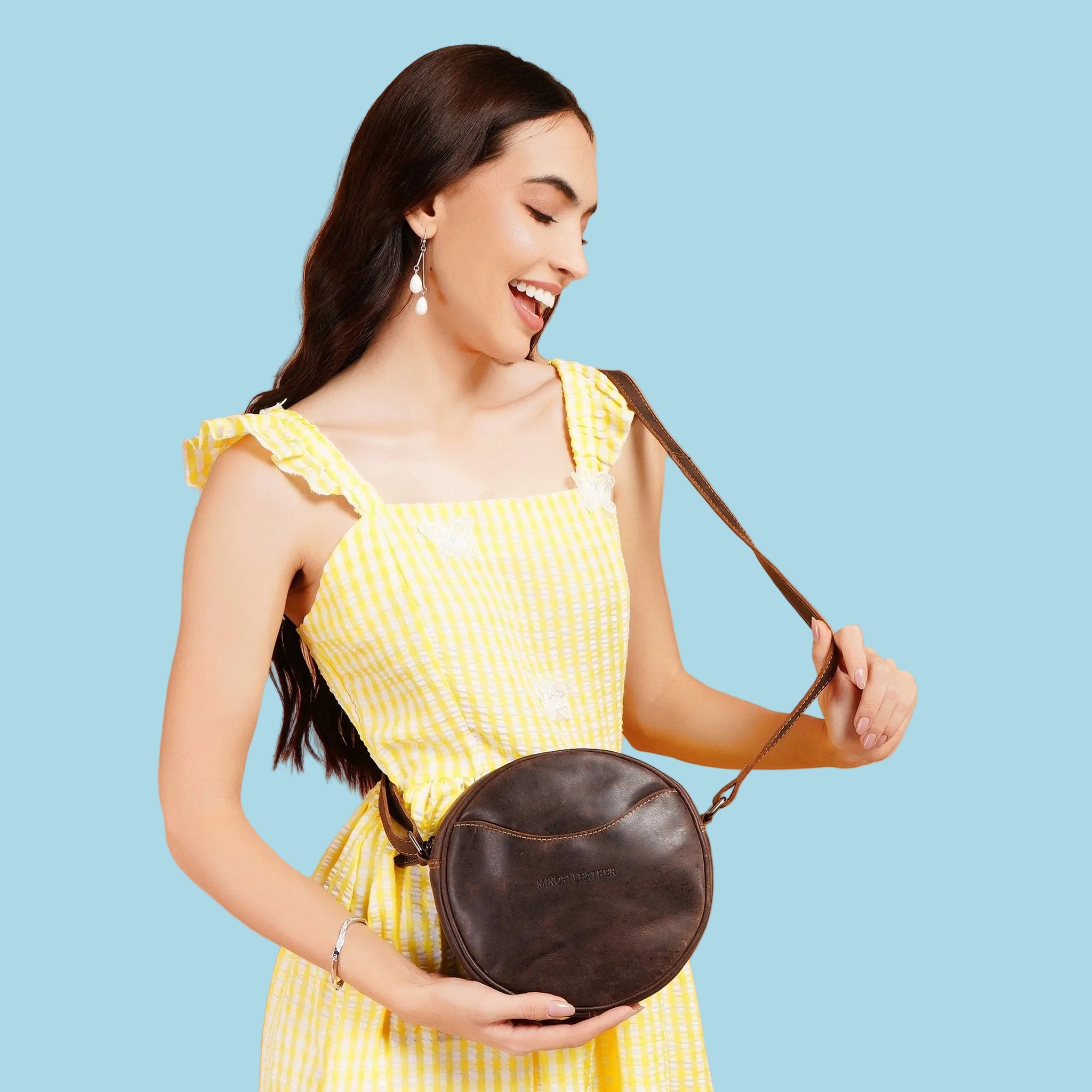 Minori Leather Luna round leather crossbody bag in chestnut and hair-on brown with a sleek design and adjustable strap.