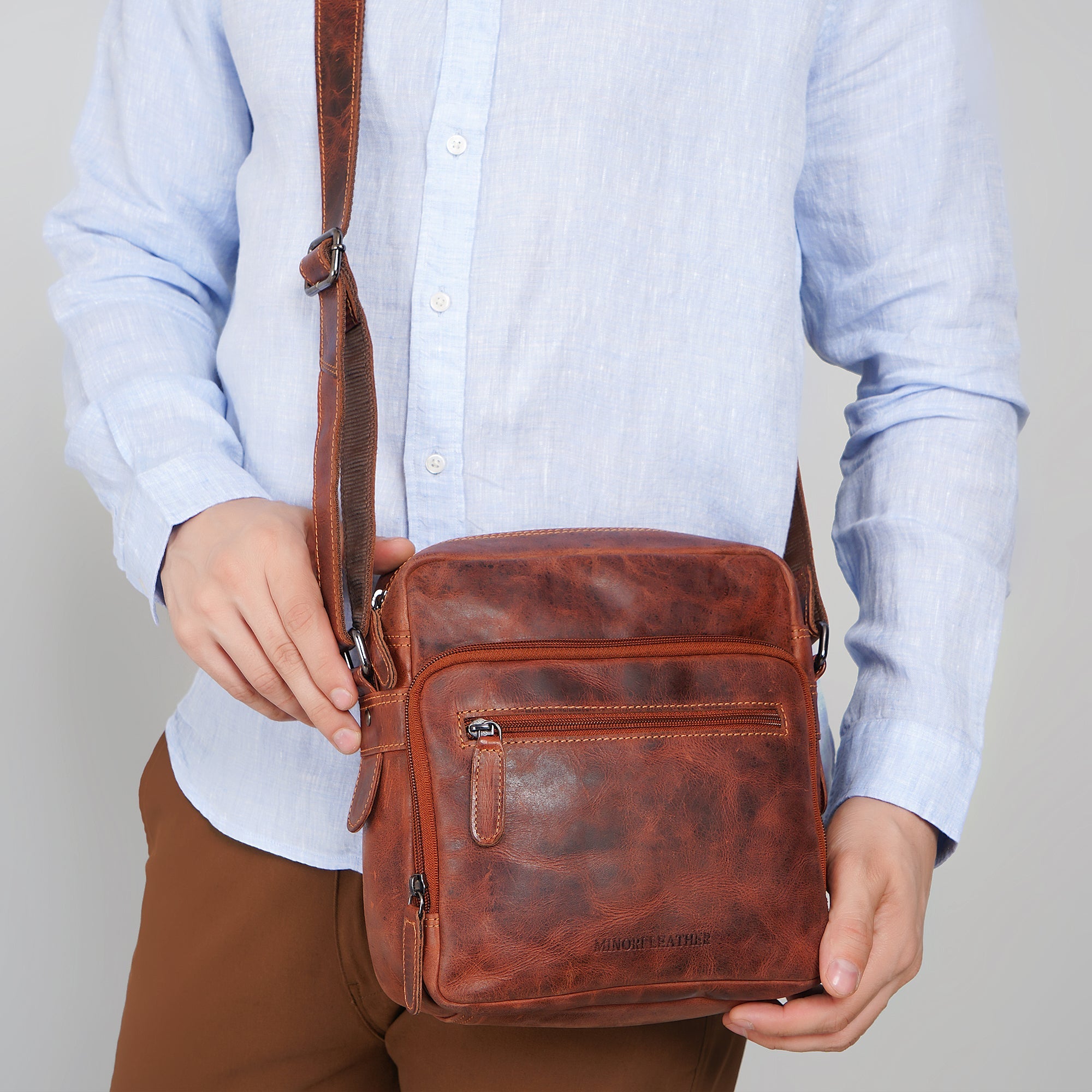 Minori Leather Harbor leather crossbody bag in chestnut with adjustable strap and silver hardware on a plain background.